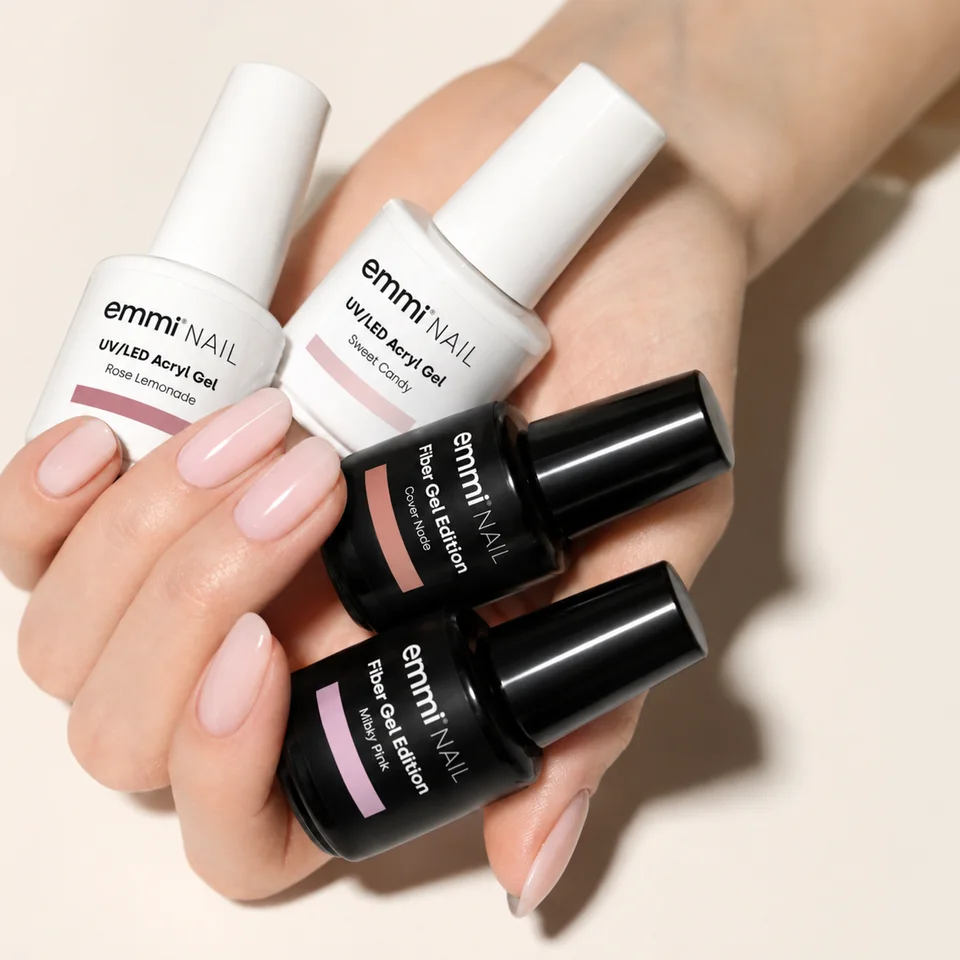 Hand with milky pink nails holding emmi®NAIL Acryl Gel and Fiber Gel bottles